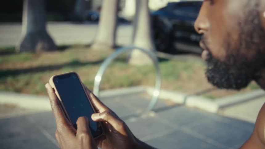 Man holds his phone with both hands and texts with his thumbs