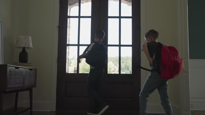 Children walk out the front door wearing backpacks