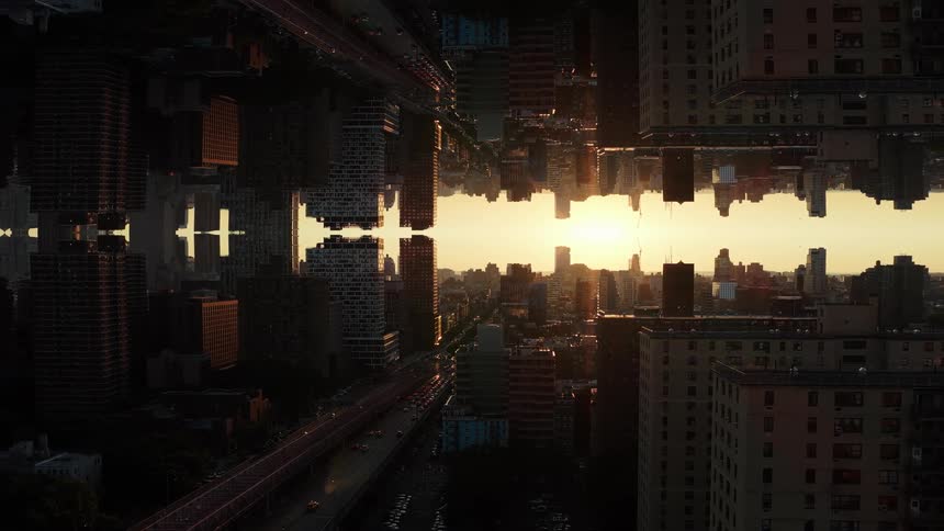 This is an aerial or highrise shot of a cityscape featuring a surreal mirrorimage effect reminiscent of the movie inception the buildings on the left are inverted and reflected vertically against the buildings on the right creating a symmetrical can