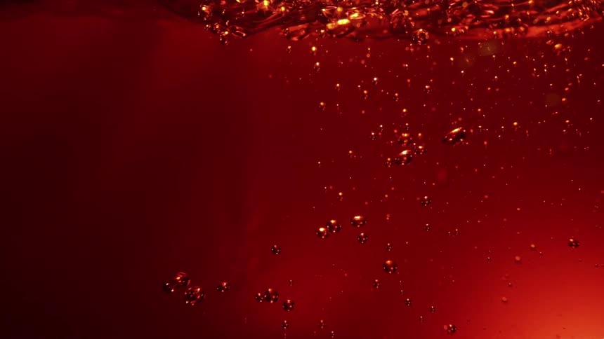Numerous air bubbles are rapidly rising through a deep bright red liquid creating a turbulent intense and abstract visual in a singlecolor fluid background