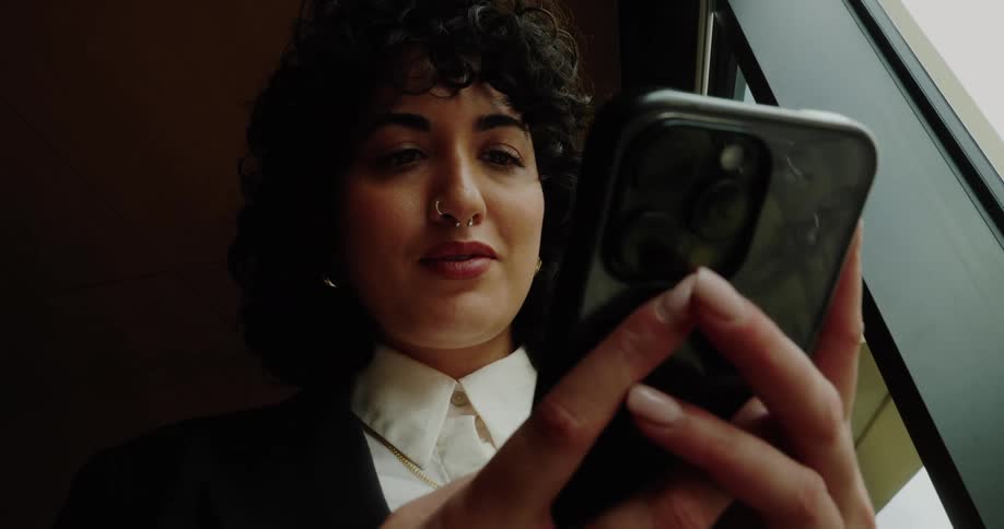 Woman uses her phone while standing near the office window