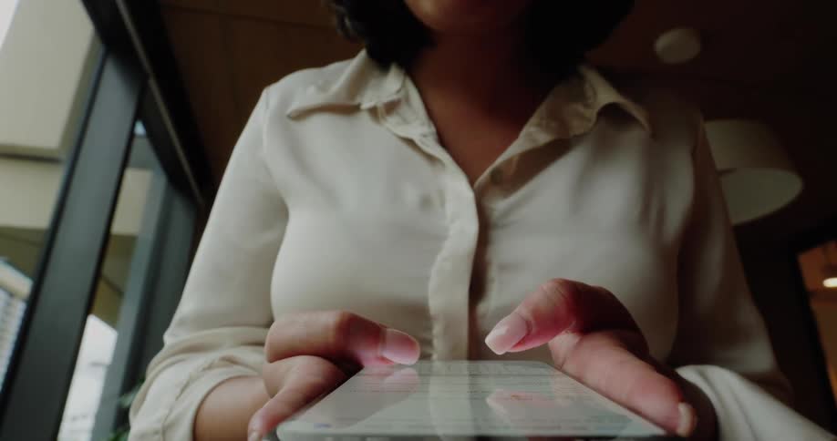 Fingers swipe across a smartphone as the person uses the device indoors