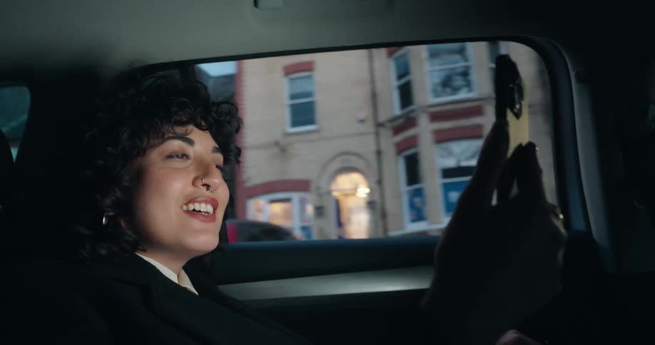 A woman is talking into her cellphone as she rides in a car