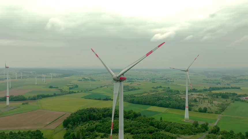 Turbines on a wind farm spin under a cloudy sky