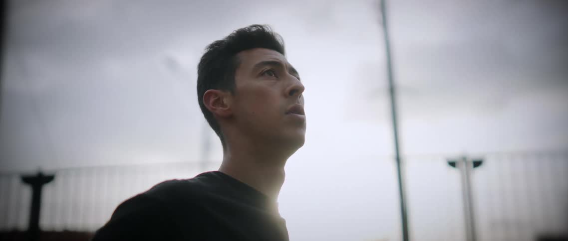 Man throws basketball under cloudy sky