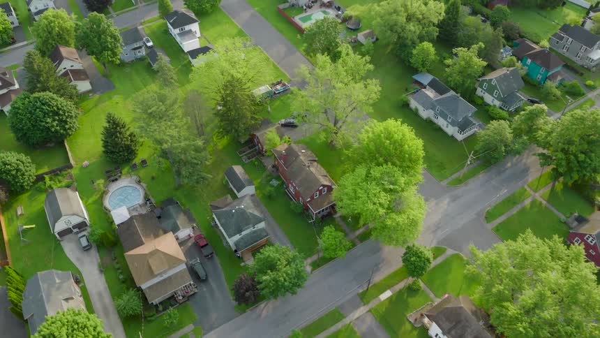 Traversing over a small town neighborhood with a variety of family homes surrounded by lush yards and mature trees