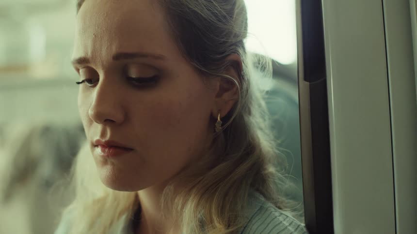 Womans softly lit face shows a downcast melancholy expression