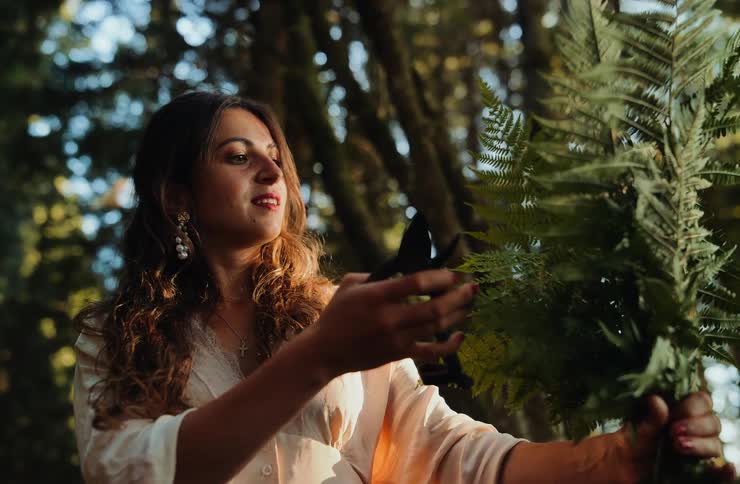Woman holding large leaves in a forest area