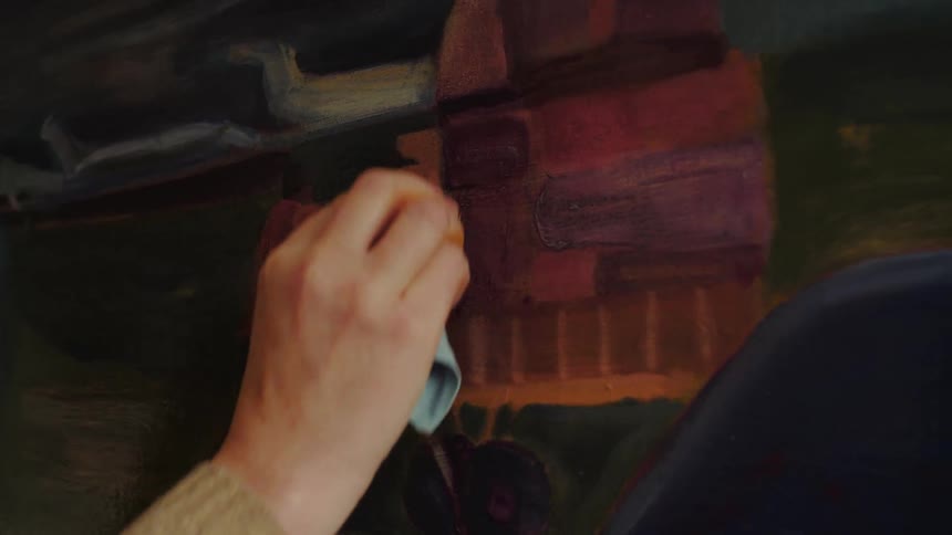 Hand applying brushstrokes on a canvas with dark and earthy tones
