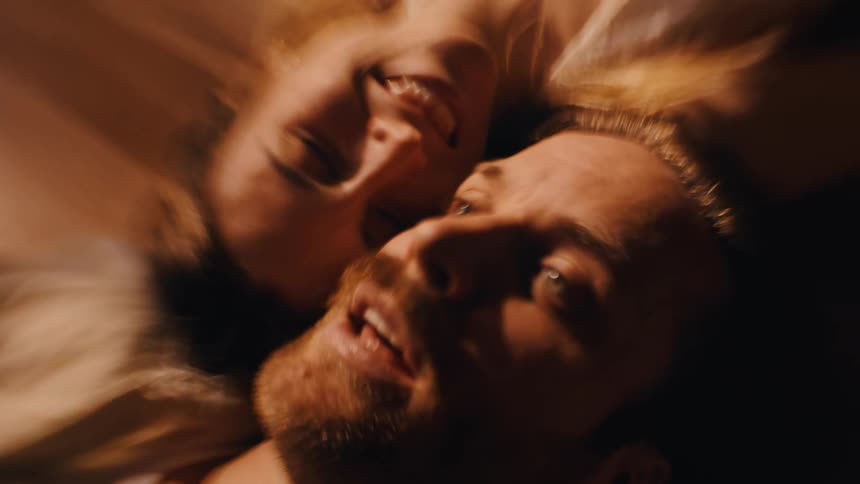 Couple lying side by side smiling under warm soft light