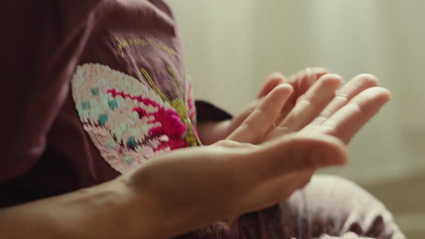 Close up of a young woman playing with a baby while carrying them on their thighs in a room during daytime