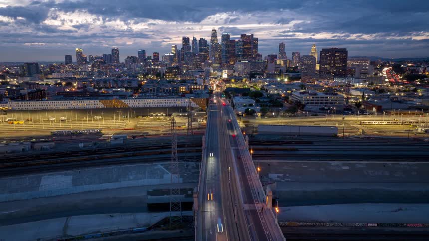 Aerial view of Los Angeles at dusk with a bridge and busy roads