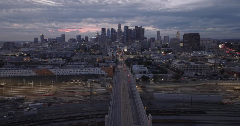 Los Angeles skyline with an overhead bridge spanning the Los Angeles River glowing in the light of sunset