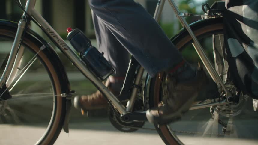Close up of a man cycling through a street in a suburban city during daytime