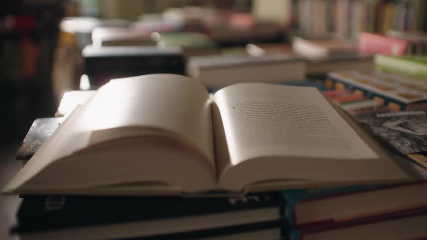 Open book resting on a stack of volumes with pages flipping rapidly