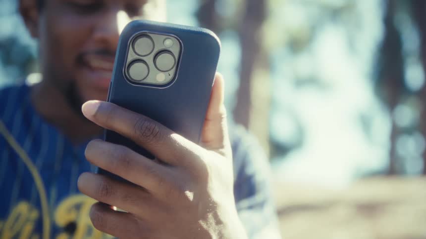 The man smiles while waving his cell phone