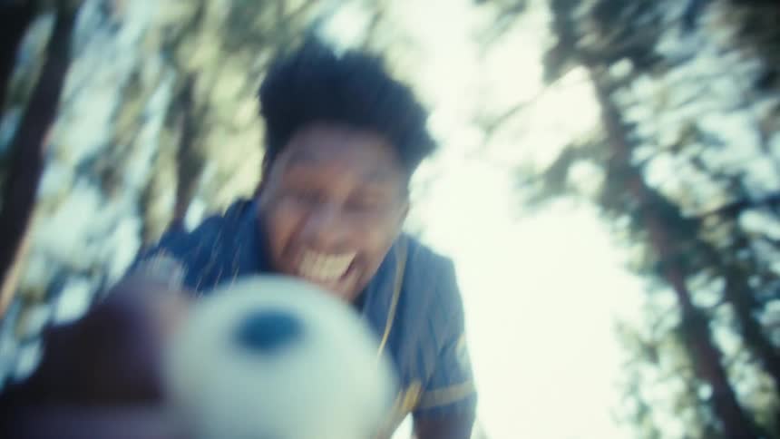Man sitting on a park bench happily throws the ball brought by a pet on a sunny day