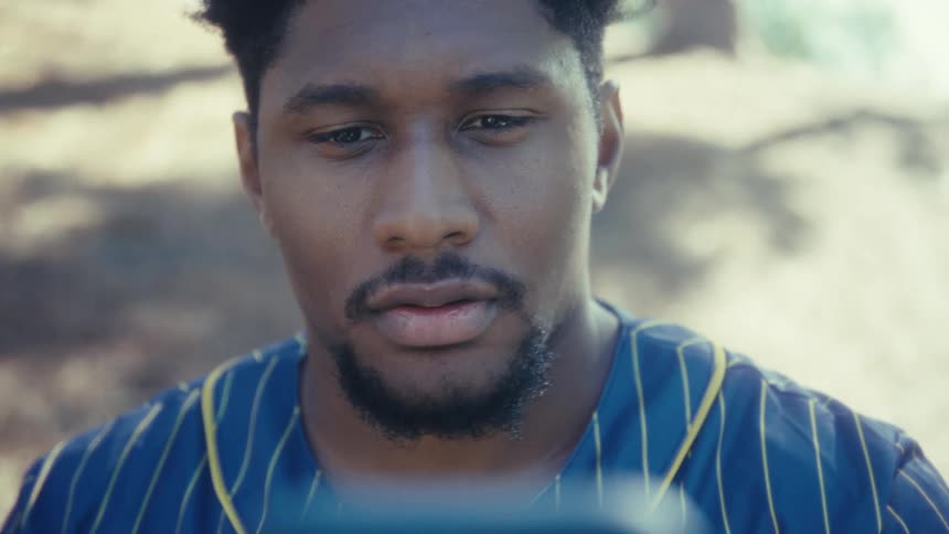 Young black man posing and taking a selfie with a smartphone on his hand outdoors during day time