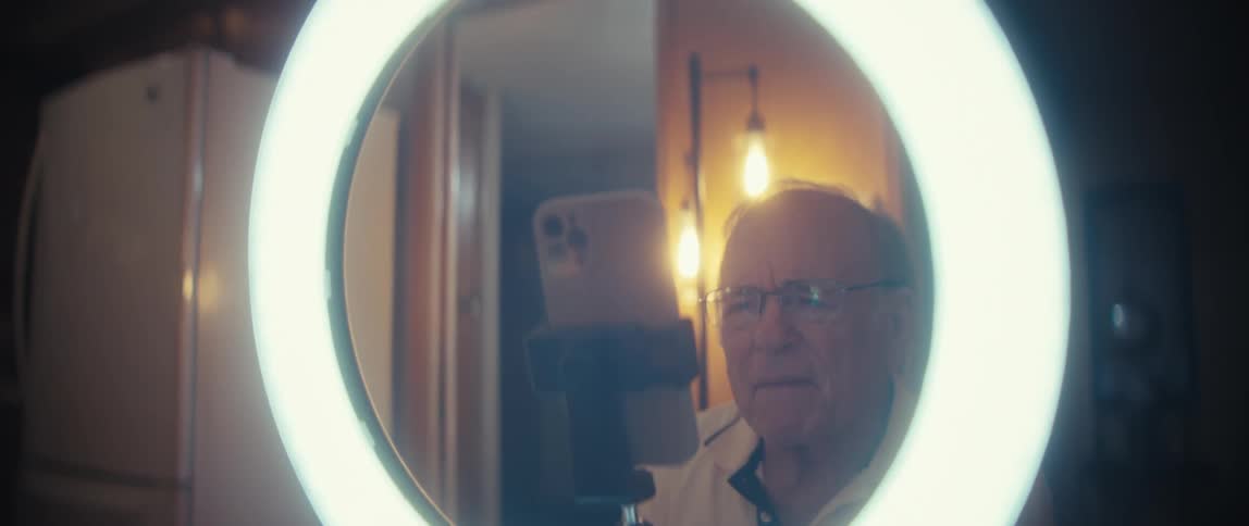 The man is looking at the phone in the circular light