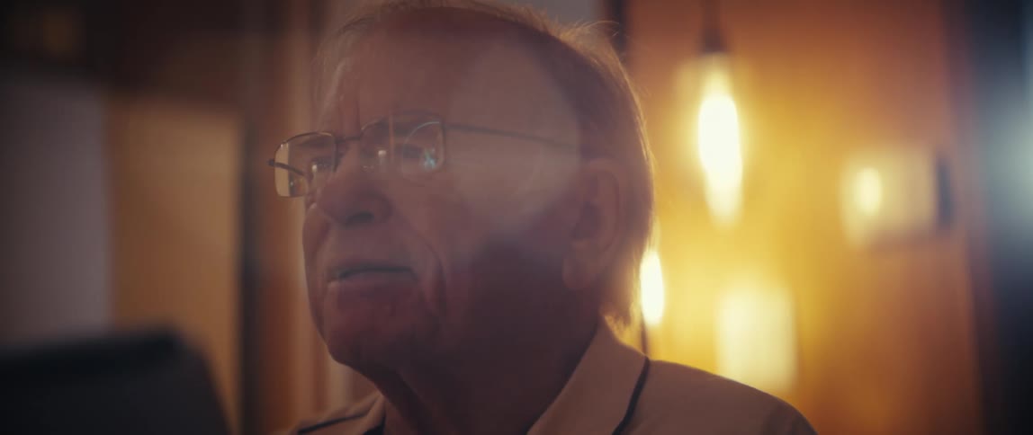 Older man wearing glasses in an indoor setting lit by a strong frontal light
