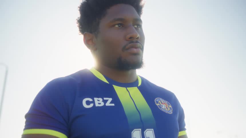 Soccer player holding a ball while facing the field under bright light