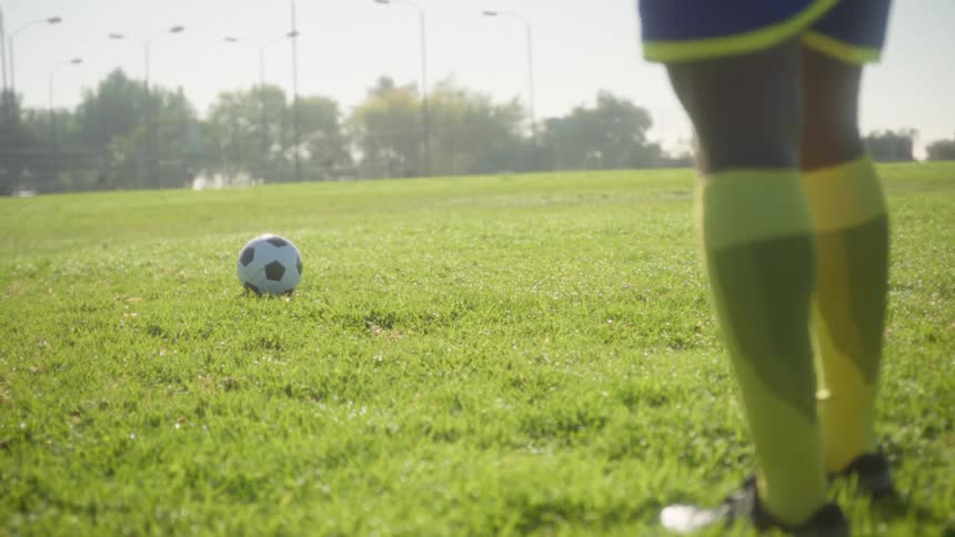 The soccer player stands near the ball on the field