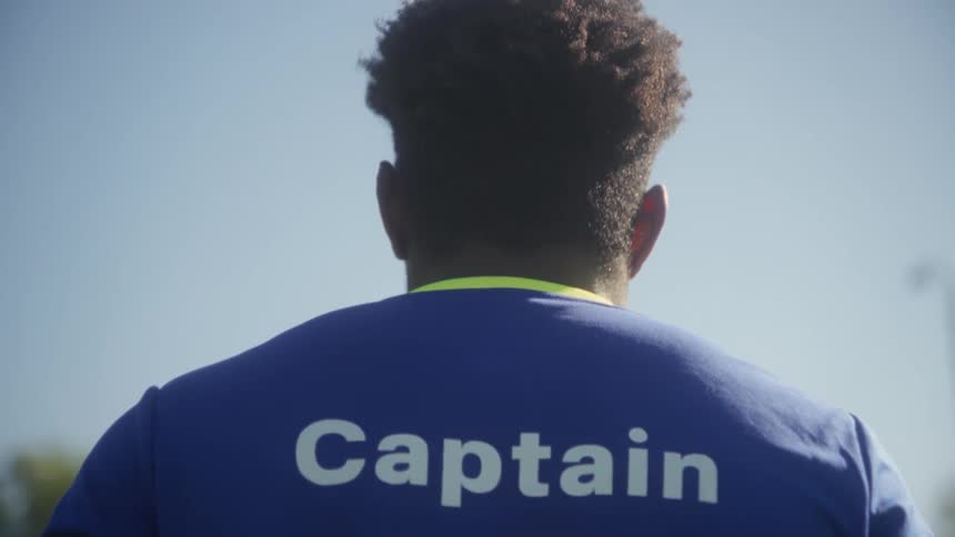 The video begins with a closeup rear view of a soccer player wearing a blue and yellow jersey with the word captain visible on the backthe camera slowly pans down to reveal the number 11 on the jersey and the player holding a classic black and wh