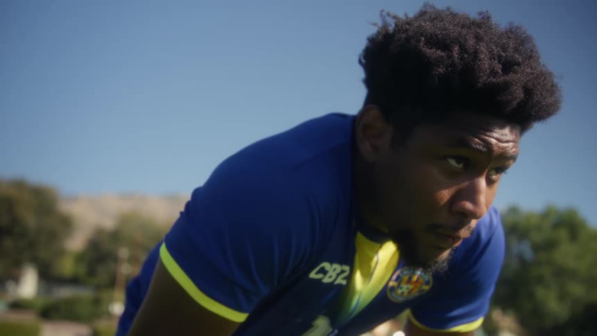Male athlete rests after exercising in a field near the mountains on a summer day