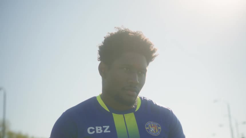 Captain number 11 jersey carrying a soccer ball on a sunlit field