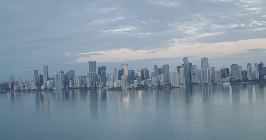 Urban skyline reflected on the water under a cloudy sky