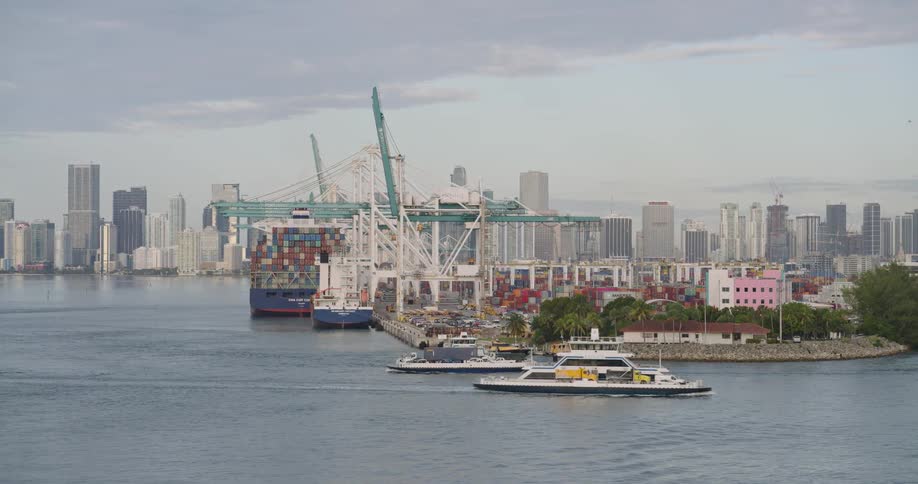 Aerial of ships moving along a channel close to a sea harbour during daytime