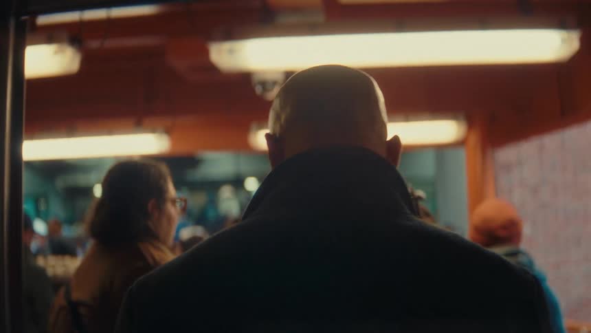 Person seen from behind walking in a lit indoor environment