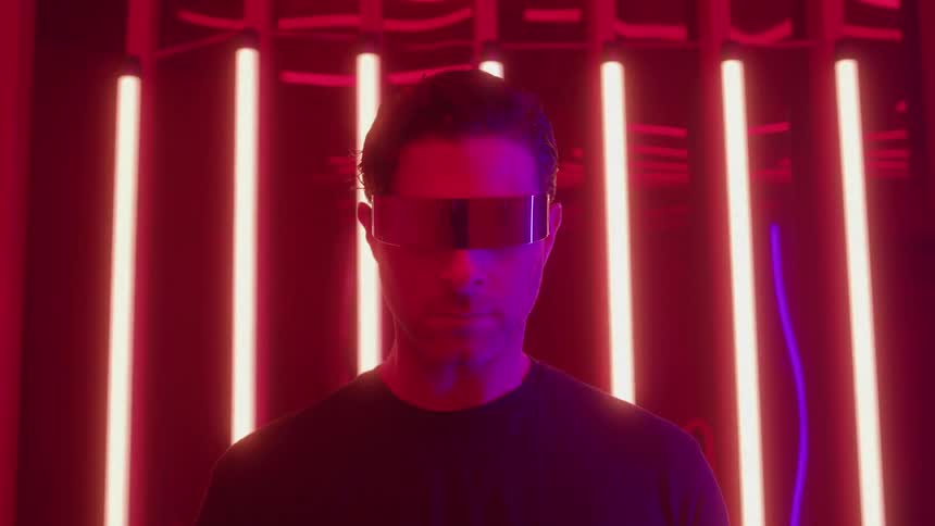 Young adult man wearing futuristic goggles in a room with colorful lights indoors
