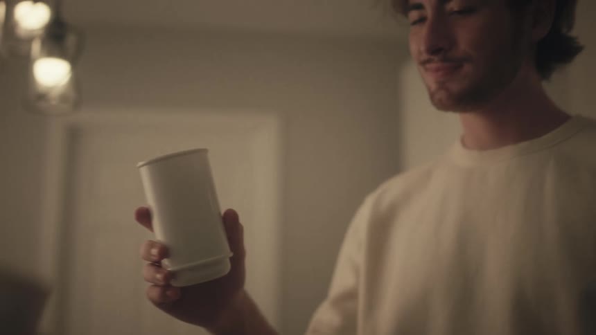 A woman hands a cup of coffee to her male companion before drinking