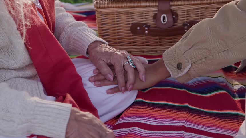 Elderly woman and a younger woman holding hands next to a basket outdoors during day time