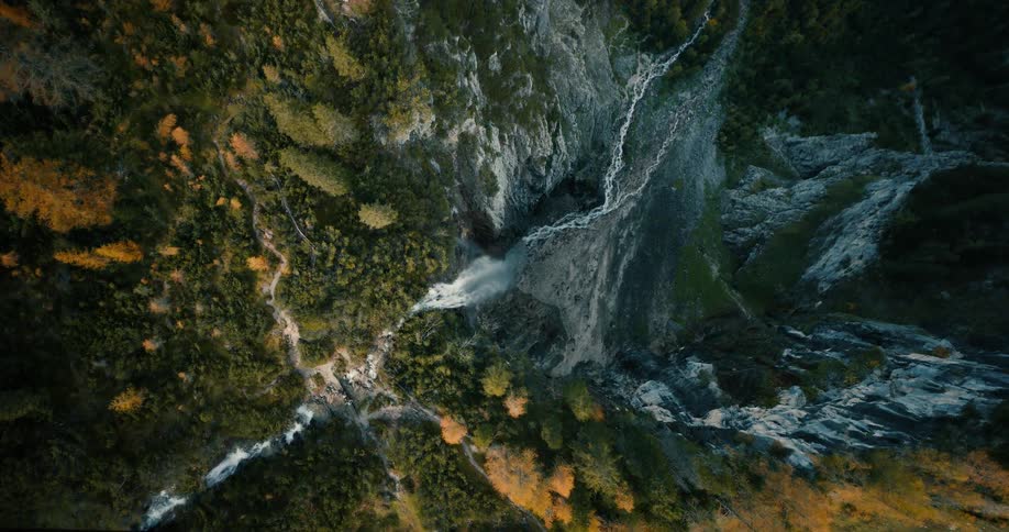 A waterfall pours water down a tall cliff in a forested area