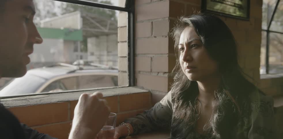 A man and woman talk by a window