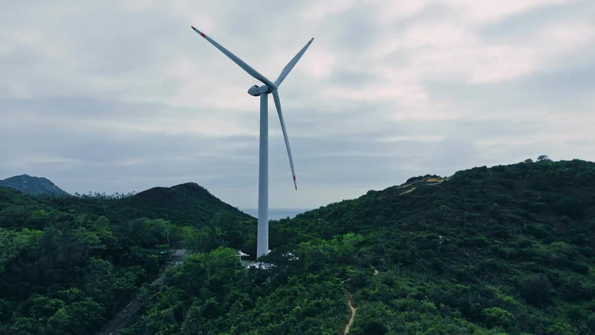 Wind turbine spins on a forested mountain
