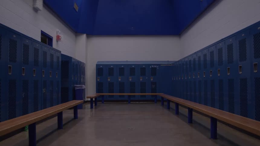 Blue lockers and a wooden bench on an empty locker room indoors