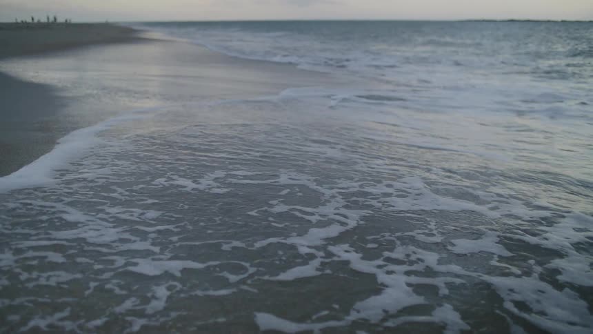 Waves roll in to shore and over the beach