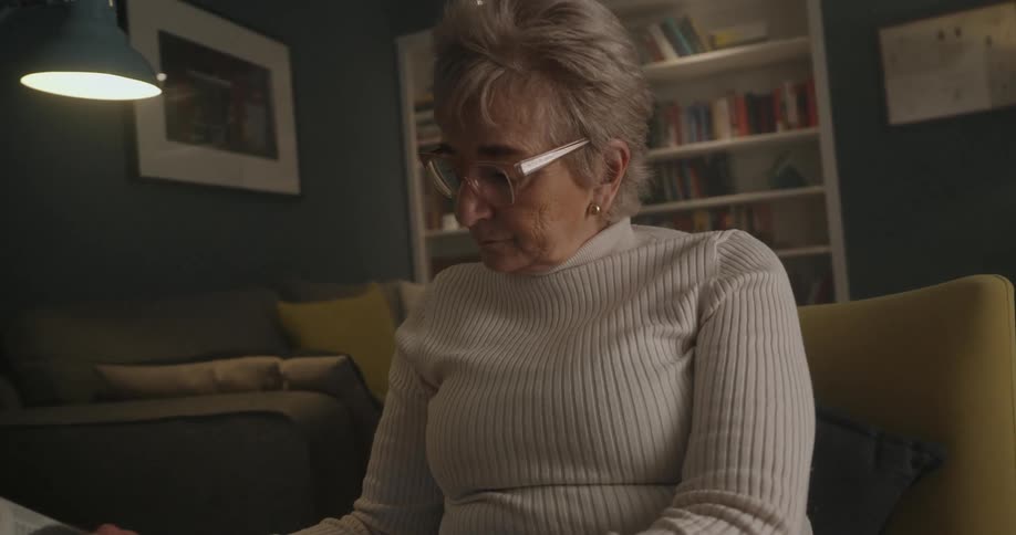 Elderly woman reading a book in a living room