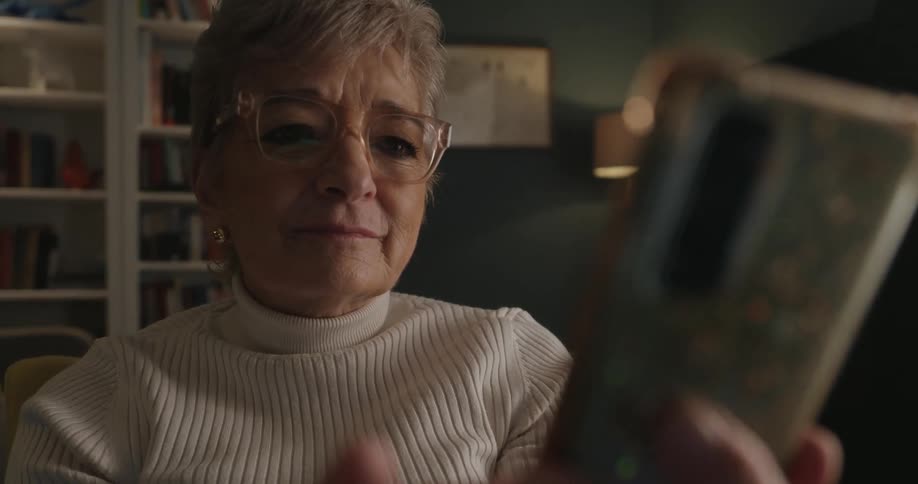 A woman sitting in her living room is texting on her phone