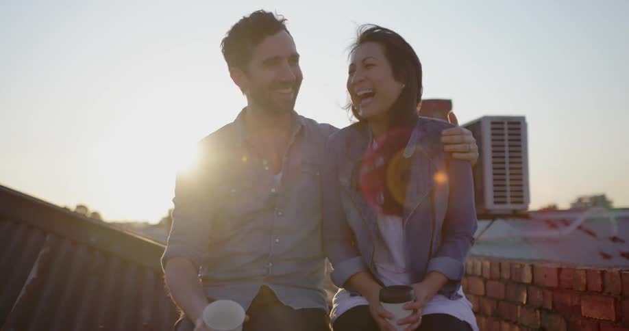 A couple talks on a windy rooftop