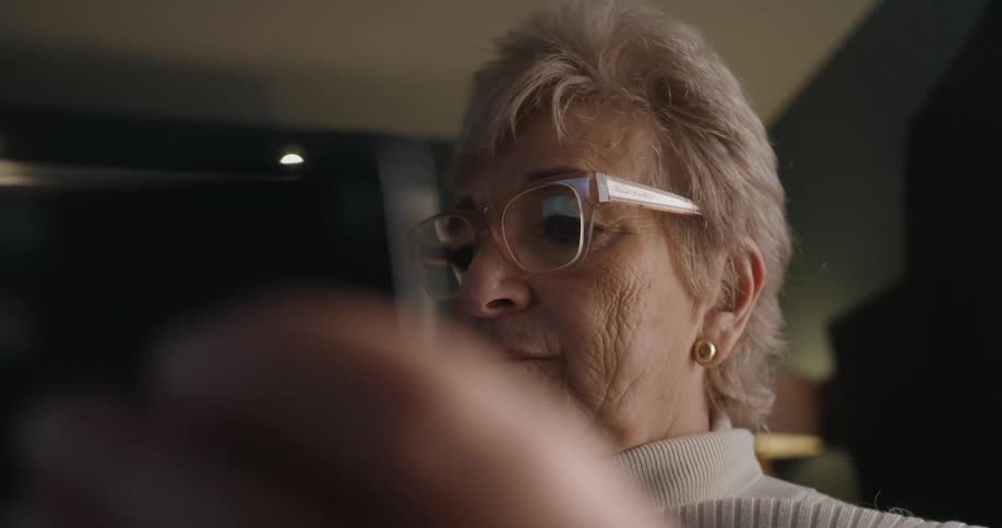 Elderly woman holding a phone in an indoor setting