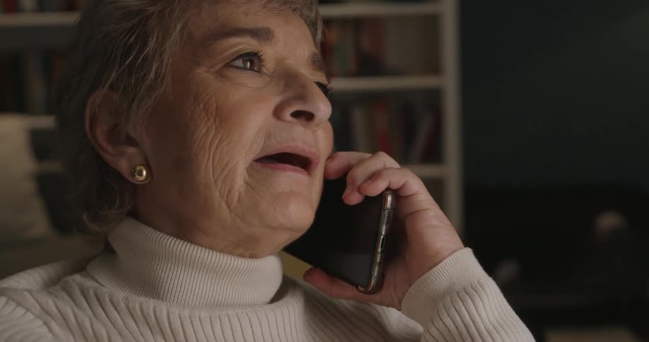 Woman looks at her phone and lifts it to her ear as she answers it and speaks