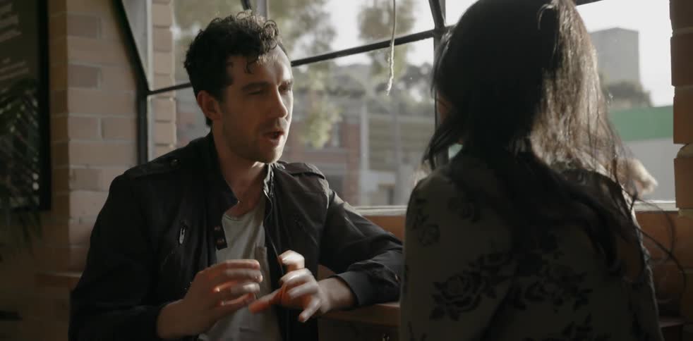 A couple sit by a window talking