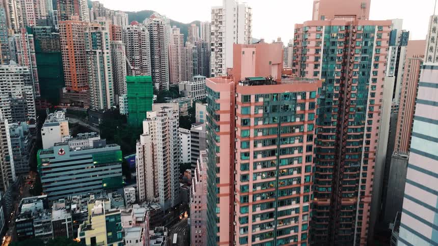 An aerial view pans up and reveals a massive densely packed city of high rise buildings stretching from foreground residential blocks toward the horizon