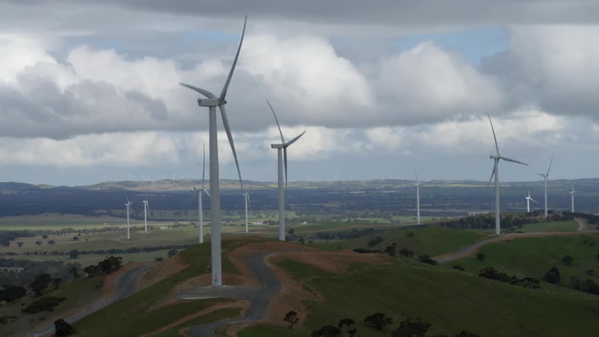 Wind turbines turning with mountains and clouds in the background