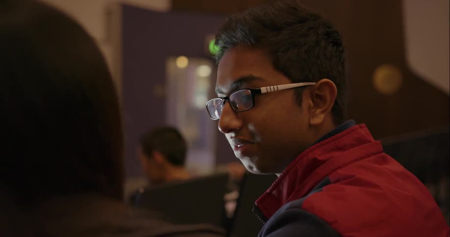 A boy is smiling and talking to a friend in class