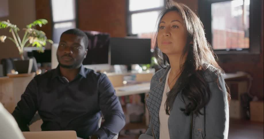 A woman nods her head as she listens to her colleagues